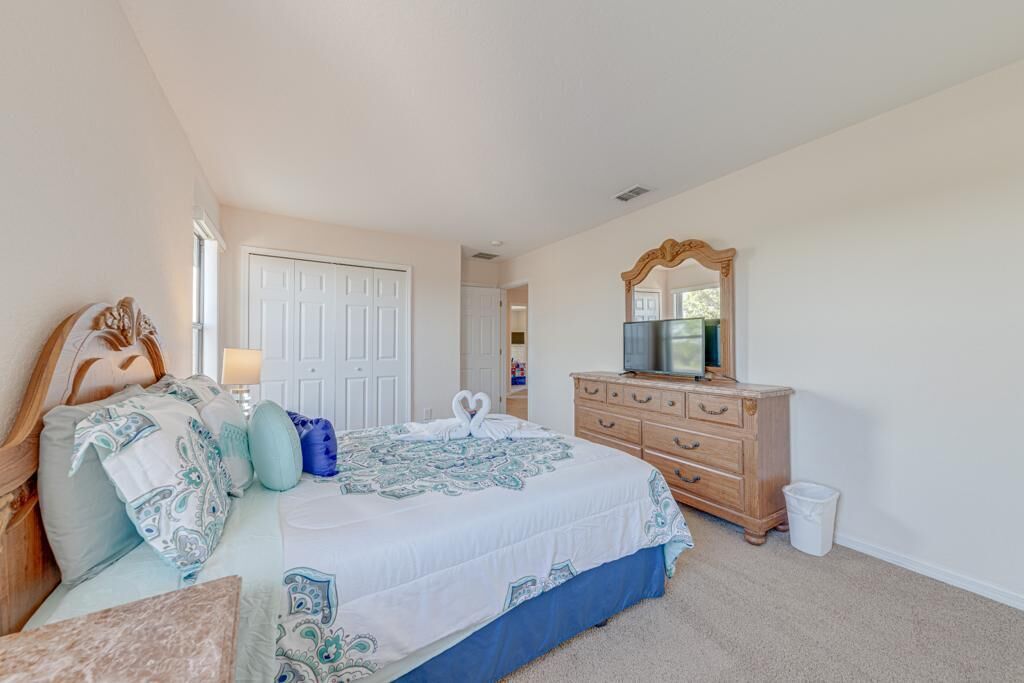 Une chambre à coucher avec un lit, une commode, un miroir et une porte.