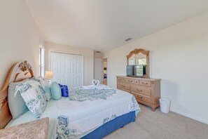 Ein Schlafzimmer mit Bett, Kommode, Spiegel und einer Tür.