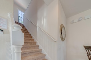 Eine Treppe mit Handlauf, einer an der Wand befestigten Uhr und einem Fenster am oberen Ende.