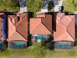 Ein mehrgeschossiges Gebäude mit einheitlich roten Ziegeldächern und einem zentralen Innenhof mit einem grünen Auto.