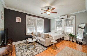 A bedroom with a bed, two bedside tables, a ceiling fan, a TV, and a large mirror. - Cute Downtown Stay near Toyota Center & Midtown (Houston)