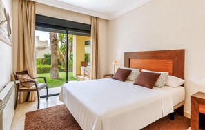 A hotel room with a large bed, a chair, a desk, and a view of a garden. - Beautiful apartment in San Javier with WiFi (San Javier)
