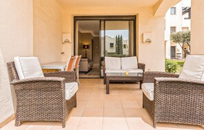 A balcony with wicker furniture, a glass door leading to an interior space, and a view of a building in the background. - Beautiful apartment in San Javier with WiFi (San Javier)
