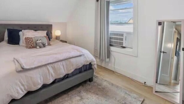 Een slaapkamer met een bed, nachtlampen, een raam met gordijnen en een deur.