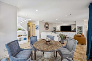A modern living room with a dining area, white sofas, a TV, and a staircase. - Remodeled & modern coastal escape duplex with pool, close to beach (Fernandina Beach)