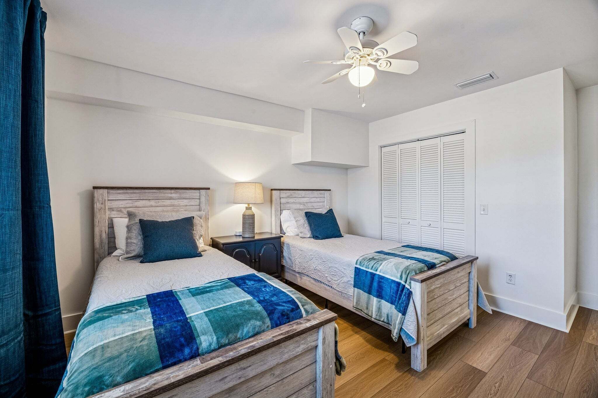 A bedroom with two beds, a ceiling fan, and a wardrobe.