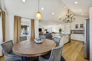 A modern kitchen with a central island, a dining area with a round table, and a chandelier. - Remodeled & modern coastal escape duplex with pool, close to beach (Fernandina Beach)