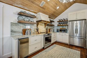 A kitchen with white cabinetry, a stainless steel refrigerator, and a marble countertop. - Spectacular renovated duplex with pool near beach (Fernandina Beach)