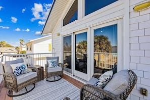 A covered patio area with wicker furniture and a view of the surrounding landscape. - Spectacular renovated duplex with pool near beach (Fernandina Beach)