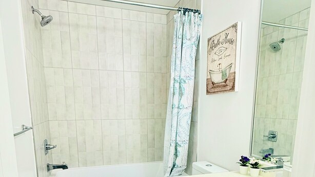 Un baño con bañera, inodoro y lavamanos con espejo.