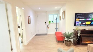 Una sala de estar con televisión, chimenea y sofá rojo.