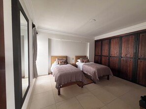A bedroom with two beds, a wardrobe, and a large mirror.