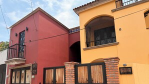 A two-story building with a red and yellow facade, wooden double doors, and a brick entrance gate. - Adorable 2-bedroom apartment in lovely Jalostotitlán perfect for relaxing (Jalostotitlán)