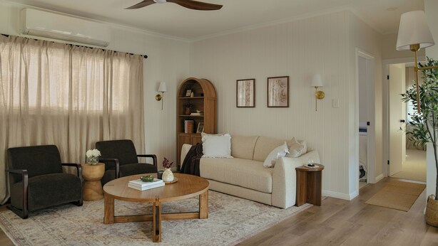 A living room with a ceiling fan, a sofa, a coffee table, a bookshelf, and a lamp. - The Butcher's Cottage | New Barossa Valley Stay (Williamstown)