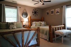 A bedroom with two beds, a wooden headboard, a nightstand, a lamp, a mirror, and framed pictures on the wall.