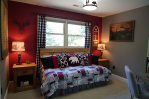 A bedroom with a wooden headboard, a checkered bedspread, and two bedside lamps.