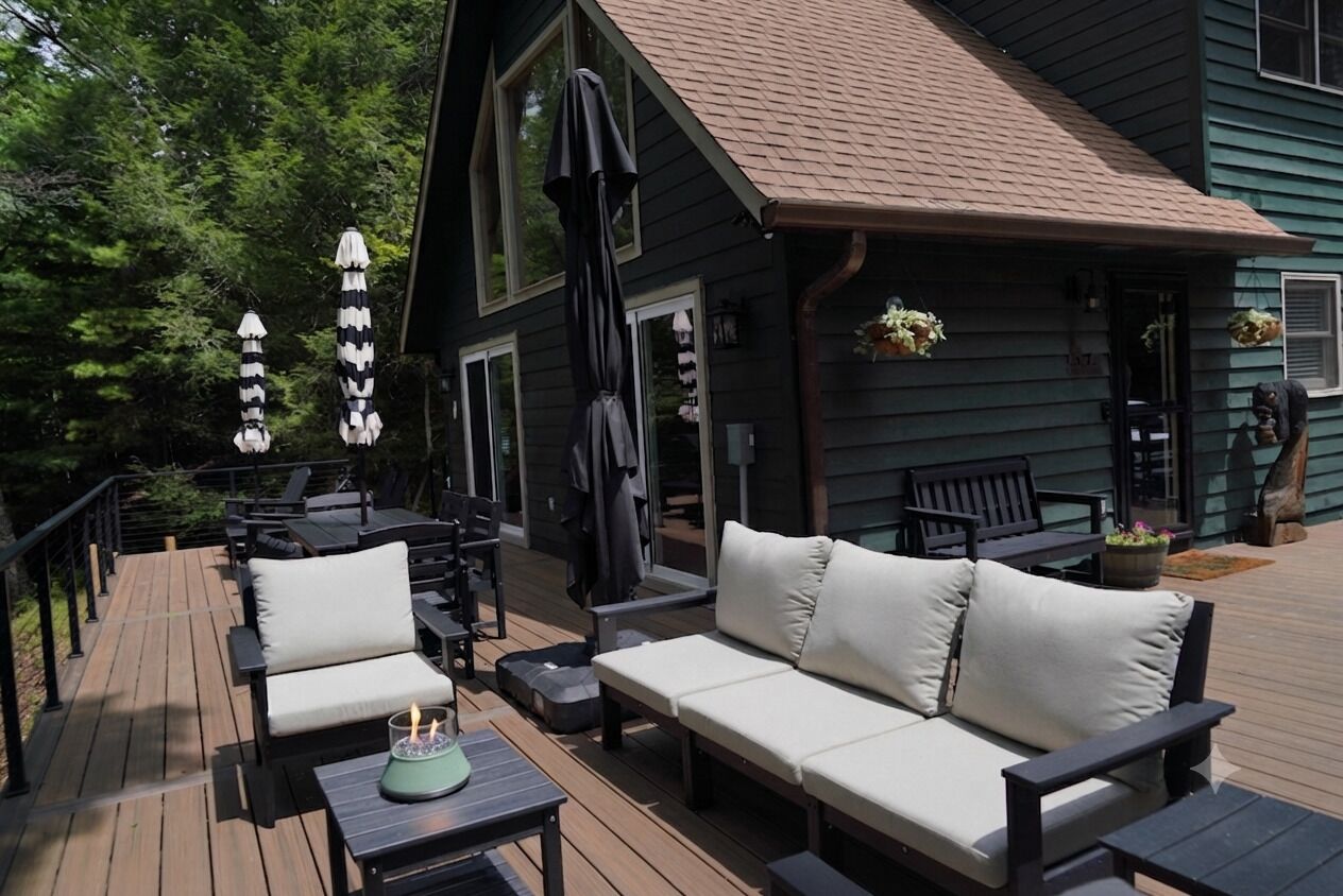 A deck with outdoor furniture, including a sofa and chairs, and a table with a candle.