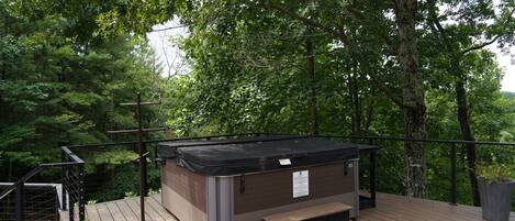 A hot tub on a wooden deck surrounded by trees.