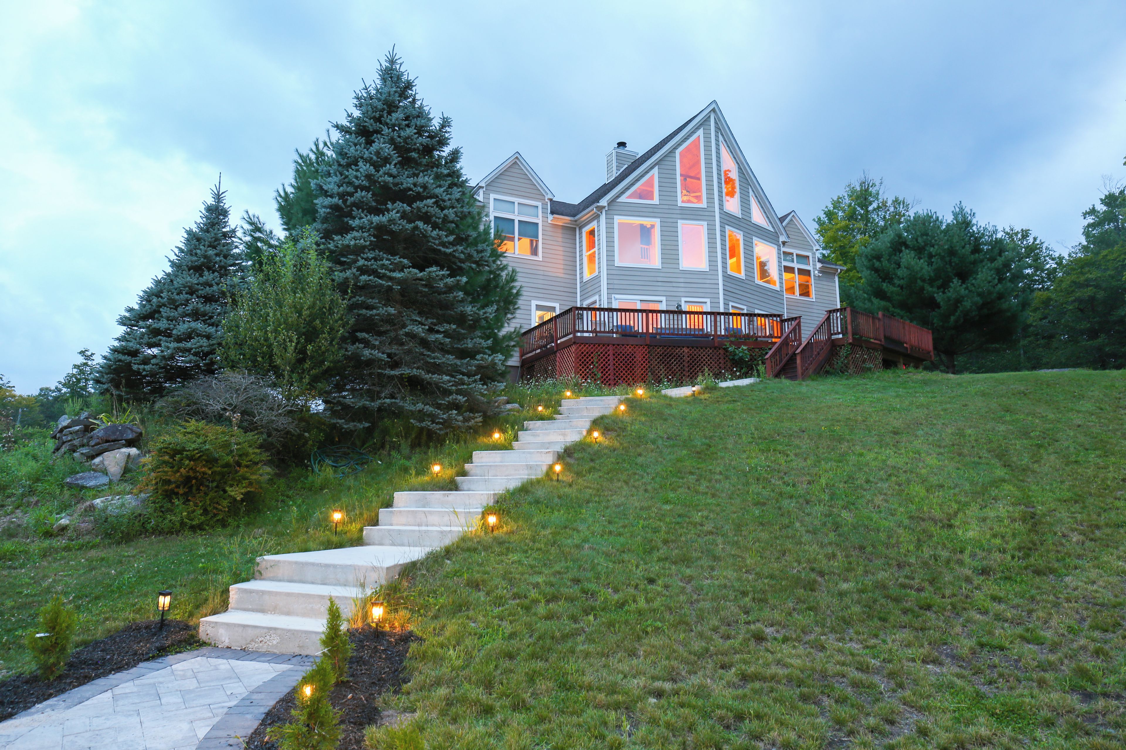 Une maison à deux étages avec un escalier en pierre menant à une terrasse en bois.