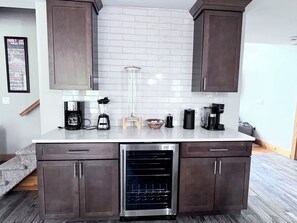 A compact kitchen with dark wood cabinets, a built-in dishwasher, and various appliances on the countertop.