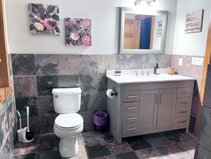 Un baño con inodoro, lavabo y mueble, con azulejos de mármol y motivos florales.
