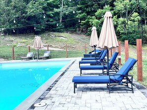 A swimming pool with lounge chairs and umbrellas.