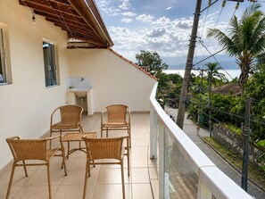 A balcony with wicker chairs, a small sink, and a view of the street and greenery. - Casa & Mar Ilhabela- SP - Brazil (Ilhabela)