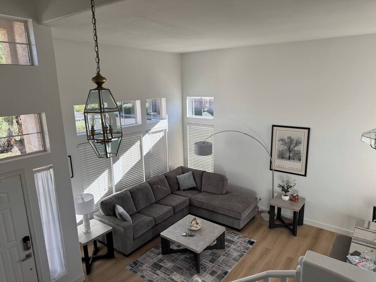 Ein modernes Wohnzimmer mit einer Eckcouch, einem Couchtisch, einer Stehlampe und einem gerahmten Bild an der Wand.