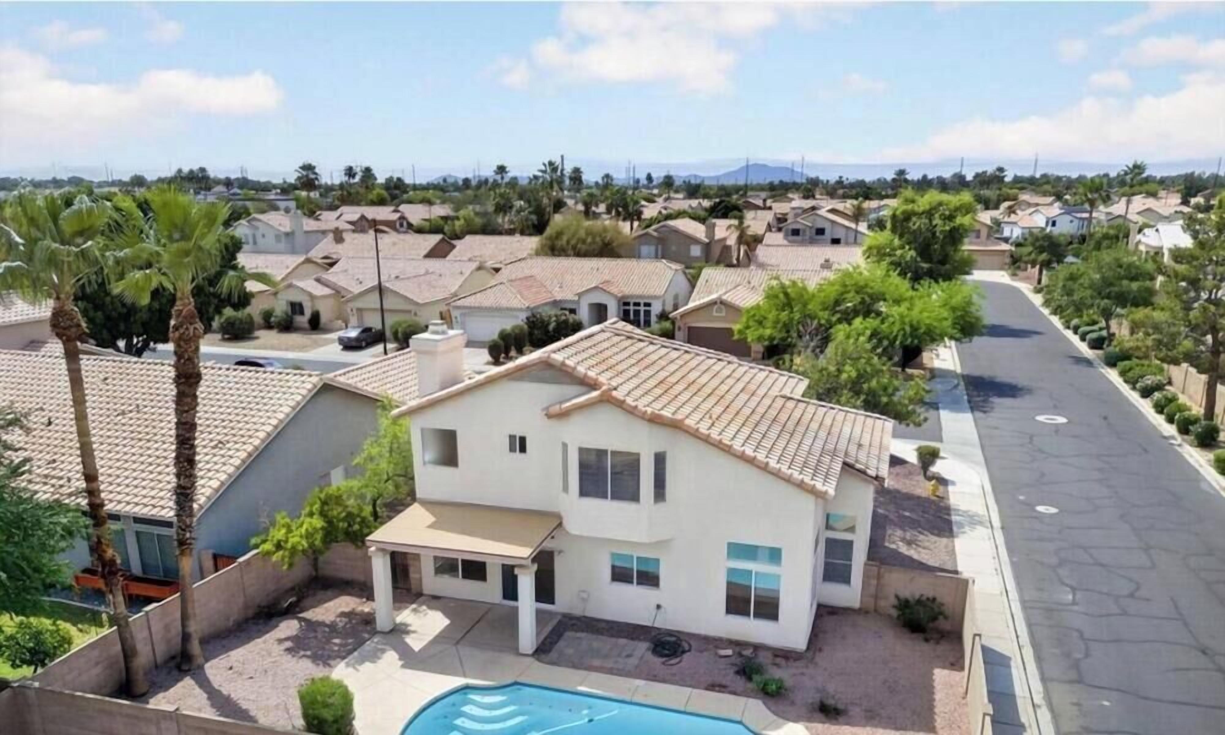 A residential area with houses, a swimming pool, and a clear sky.