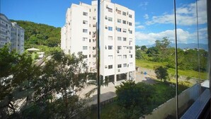 Un edificio de varios pisos con techo plano, rodeado de vegetación y otros edificios.