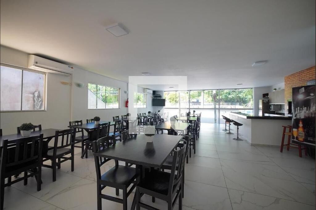 Un grand espace dédié à la salle à manger, avec plusieurs tables et chaises, un coin cuisine doté d’un comptoir et de grandes fenêtres laissant entrer la lumière naturelle.