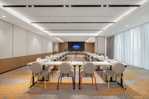 Un salón de conferencias con una larga mesa, sillas y una pantalla para presentaciones.