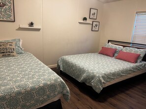 A bedroom with two single beds, a wooden floor, a white wall, and a window with blinds. - Lake Livingston 4BR Retreat with Huge Private Dock for Fishing & Boating (Onalaska)