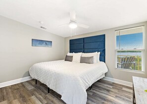 A bedroom with a bed, a ceiling fan, a window with blinds, and a painting on the wall. - Bay-view 5BR Gulf Shores home with 5.5 baths, sleeps 12, and easy beach access. (Gulf Shores)