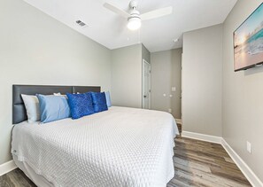 A bedroom with a bed, a ceiling fan, and a door leading to another room. - Bay-view 5BR Gulf Shores home with 5.5 baths, sleeps 12, and easy beach access. (Gulf Shores)