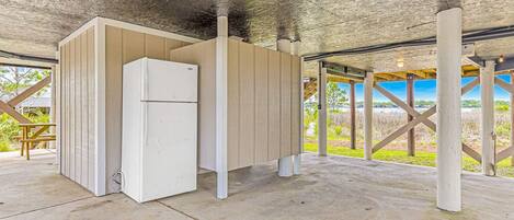 Un espacio exterior cubierto con un refrigerador blanco, bancos de madera y vistas al exterior.