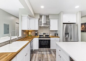 A modern kitchen with white cabinetry, a stainless steel range, and a built-in oven. - Bay-view 5BR Gulf Shores home with 5.5 baths, sleeps 12, and easy beach access. (Gulf Shores)