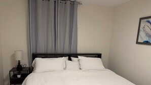 A bedroom with a bed, a nightstand, a lamp, and a painting on the wall.