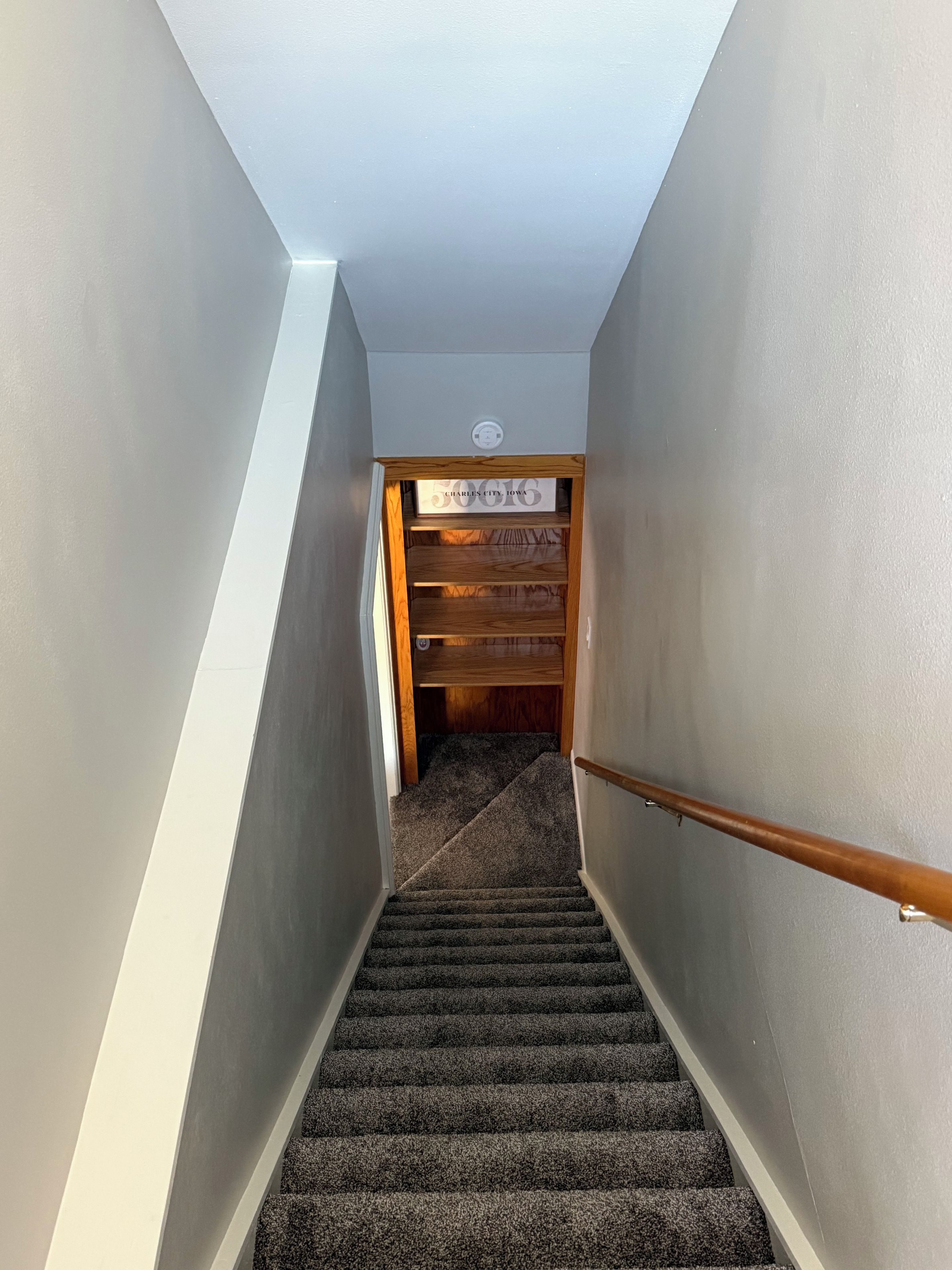 Una escalera alfombrada que lleva a un armario de madera con un letrero encima.