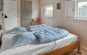 Ein Schlafzimmer mit einem hölzernen Bett, einem Stuhl, einem Fenster und einer Tür.