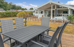 Eine Terrasse mit Tisch und Stühlen, ein überdachter Außenbereich und ein Gebäude im Hintergrund.