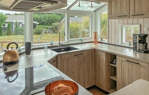 Eine moderne Küche mit einem großen Fenster, Holzschränken und einer Kaffeemaschine.