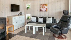 A modern living room with a fireplace, sofa, coffee table, and leather chair. - Amazing home in Bjert with sauna (Bjert)