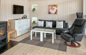 A modern living room with a fireplace, sofa, coffee table, and leather chair.
