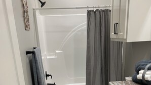 Un baño con bañera, inodoro y tocador con cajones.