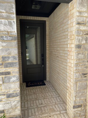 A stone-walled entrance with a dark door, a doormat, and a small step leading to the door. - Gable Retreat. Large Home. Near LA Tech & Grambling State with Garage (Ruston)