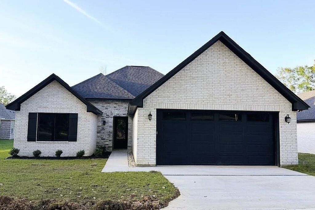 A two-story house with a garage, a front lawn, and a driveway.
