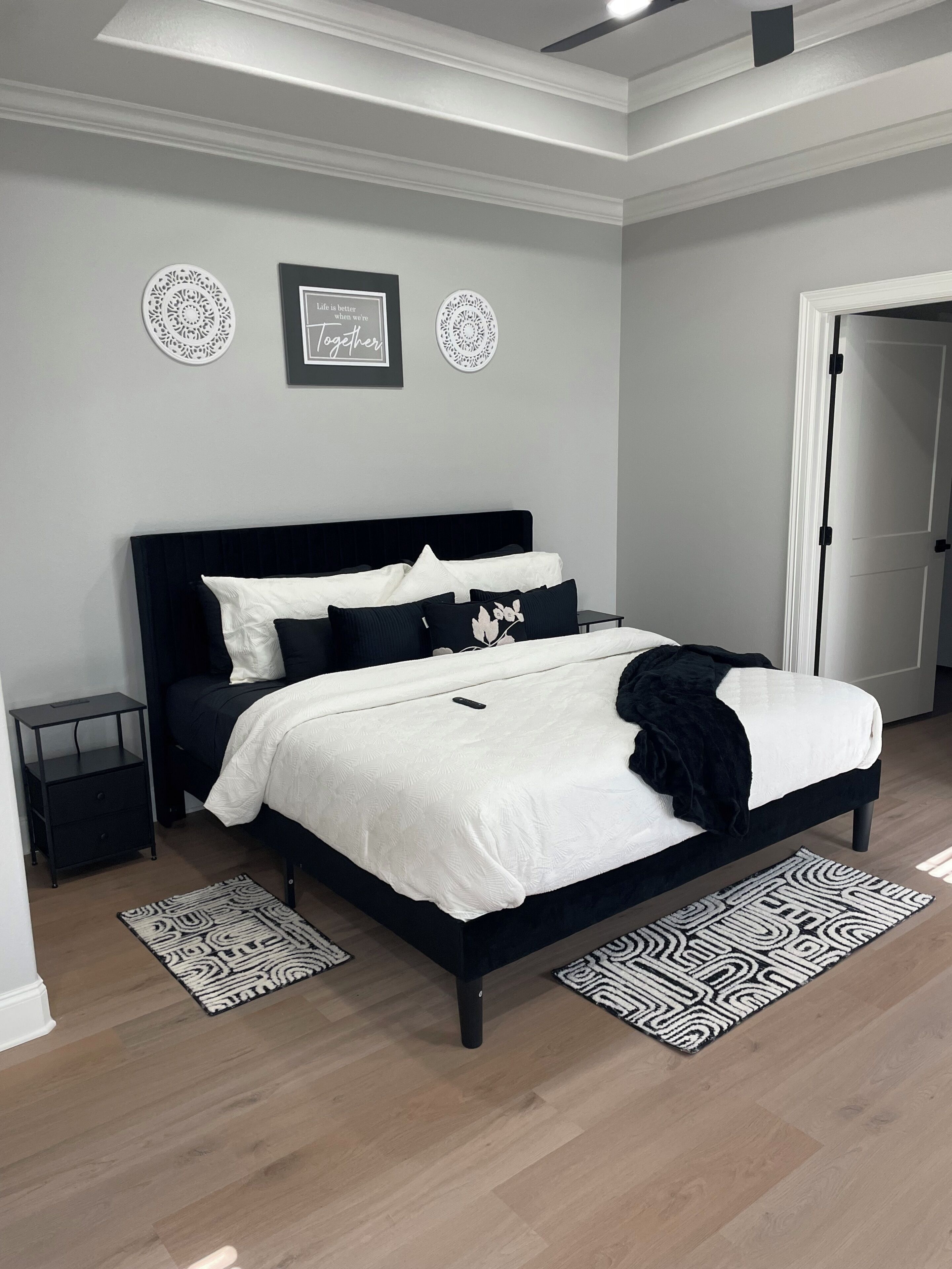 A bedroom with a black bed, white bedding, and patterned rugs.