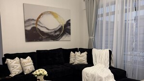 Ein modernes Wohnzimmer mit einem schwarzen Ecksofa, einem weißen Sessel, einem runden Couchtisch und einem Bild an der Wand.