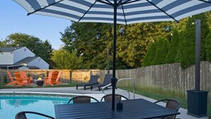 A backyard with a swimming pool, lounge chairs, a table with chairs, and an umbrella. - Pool, Hot tub and Gameroom! (Columbus)
